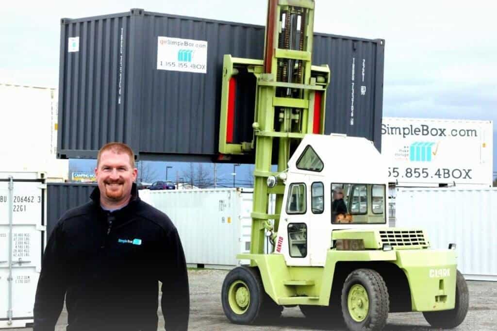Shipping Container loaded with forklift. The forklift is green and the container is gray.