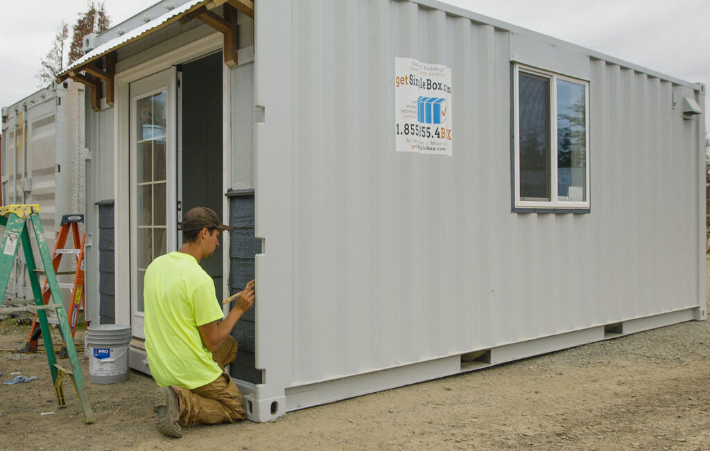 a Simple Box employee paints a modified shipping container