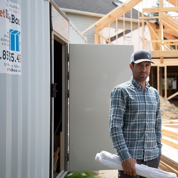 Man standing next to a rented storage container in front of a house that is under construction