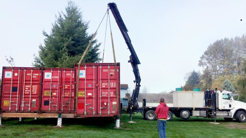 Crane lifting a red shipping container.