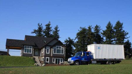 Truck delivers a shipping container to a house.