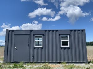 20ft shipping container modified with people/pedestrian door and two windows.