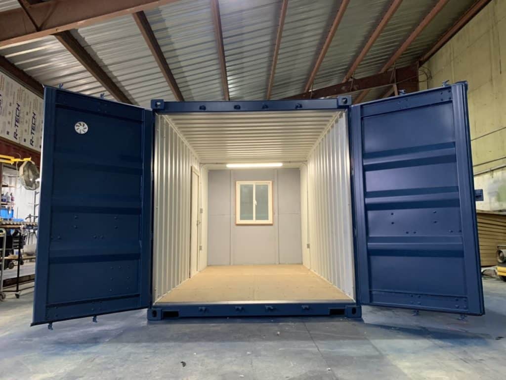 Modified shipping container with overhead light and a window with custom paint in dark blue.
