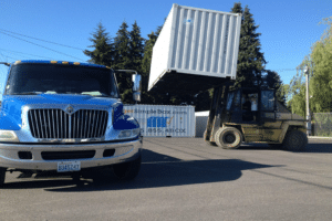 Shipping container being delivered with flatbed