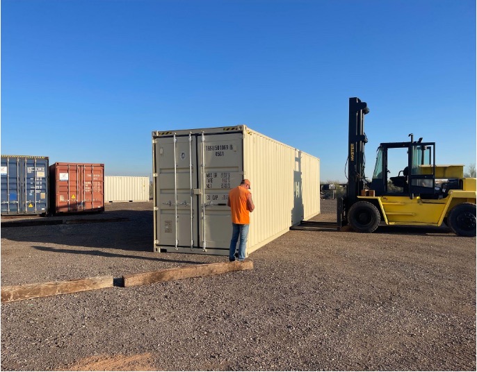 Tan shipping container with yellow forklift