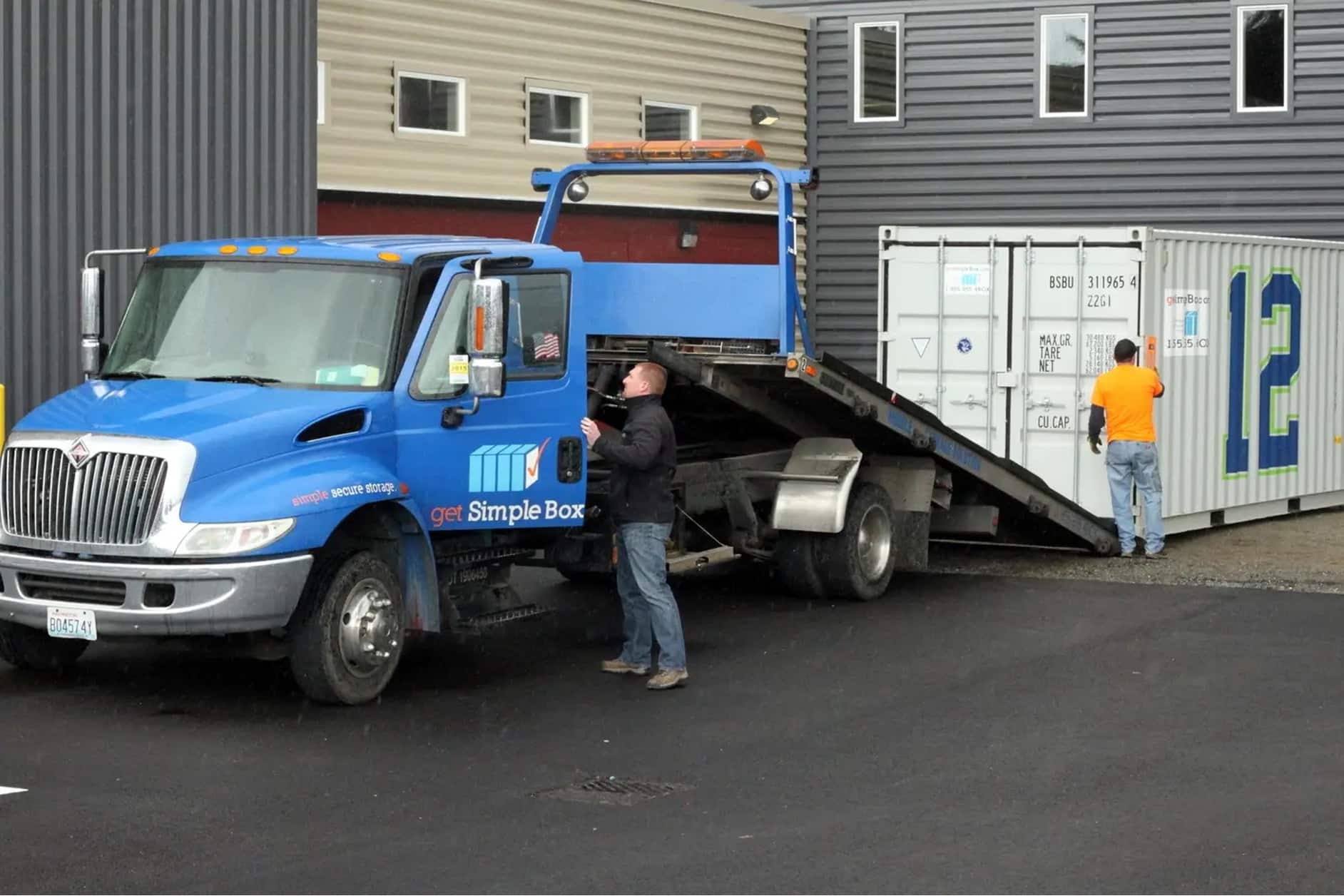 Man unloading shipping container on the ground with a truck