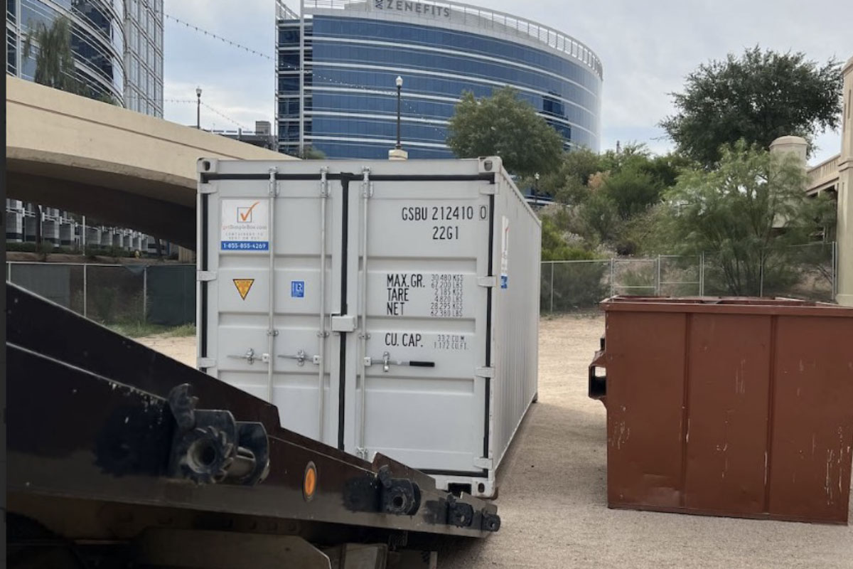 20 foot shipping container being delivered beside a red box - determining if buying a shipping container is the right move for you