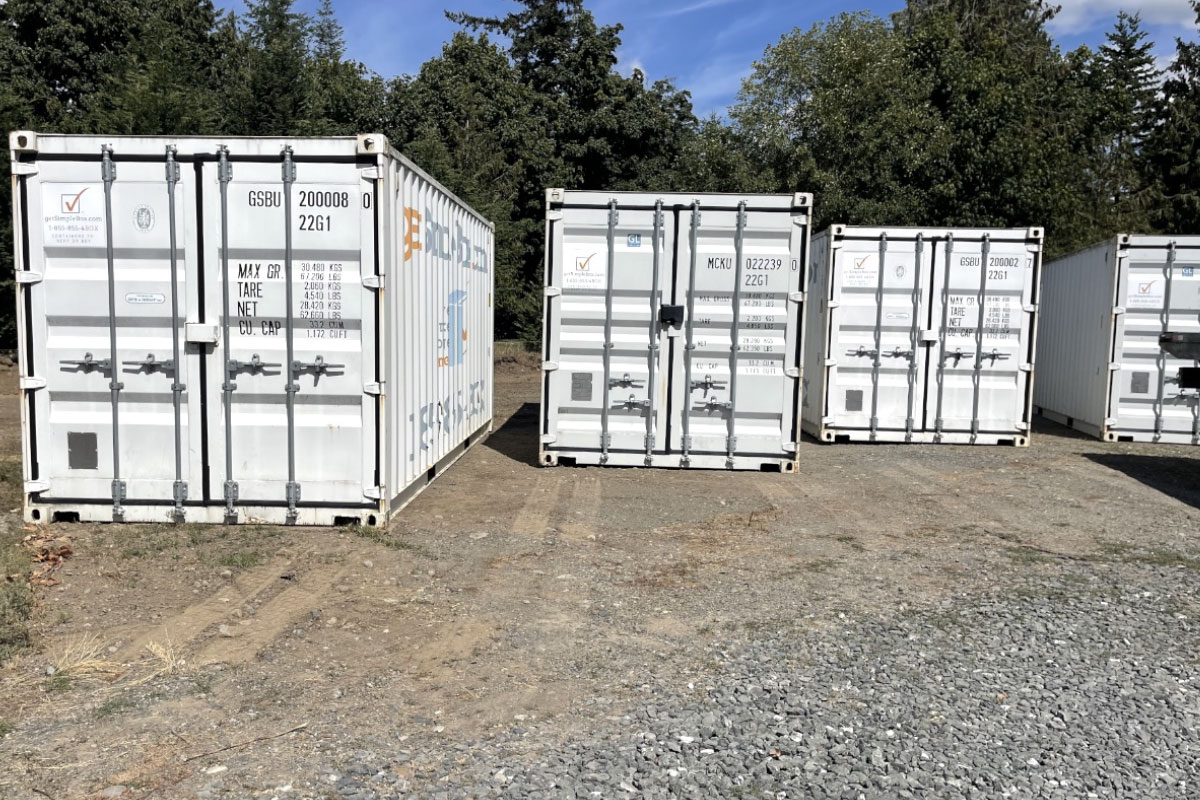 This photo answers the question how fast can I rent a shipping container by displaying an example 4 white containers in a yard available for rent