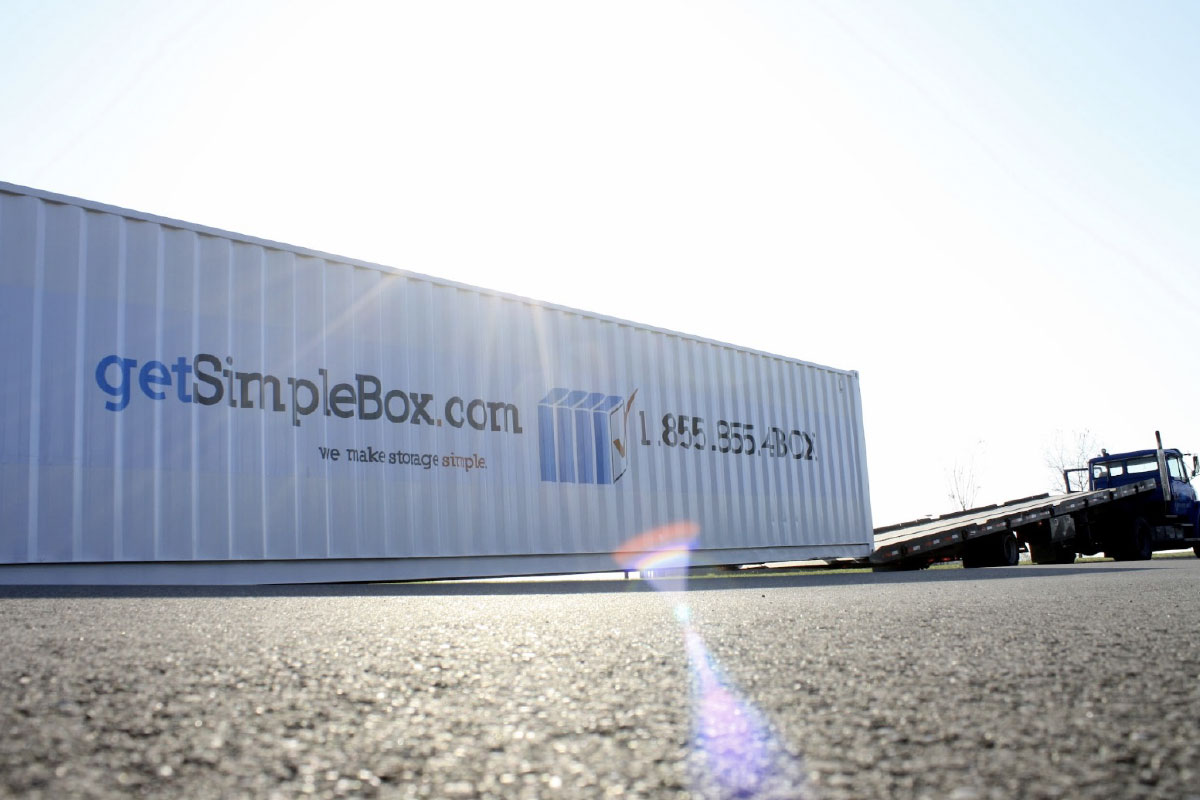 white and long 40 foot shipping container with truck unloading it
