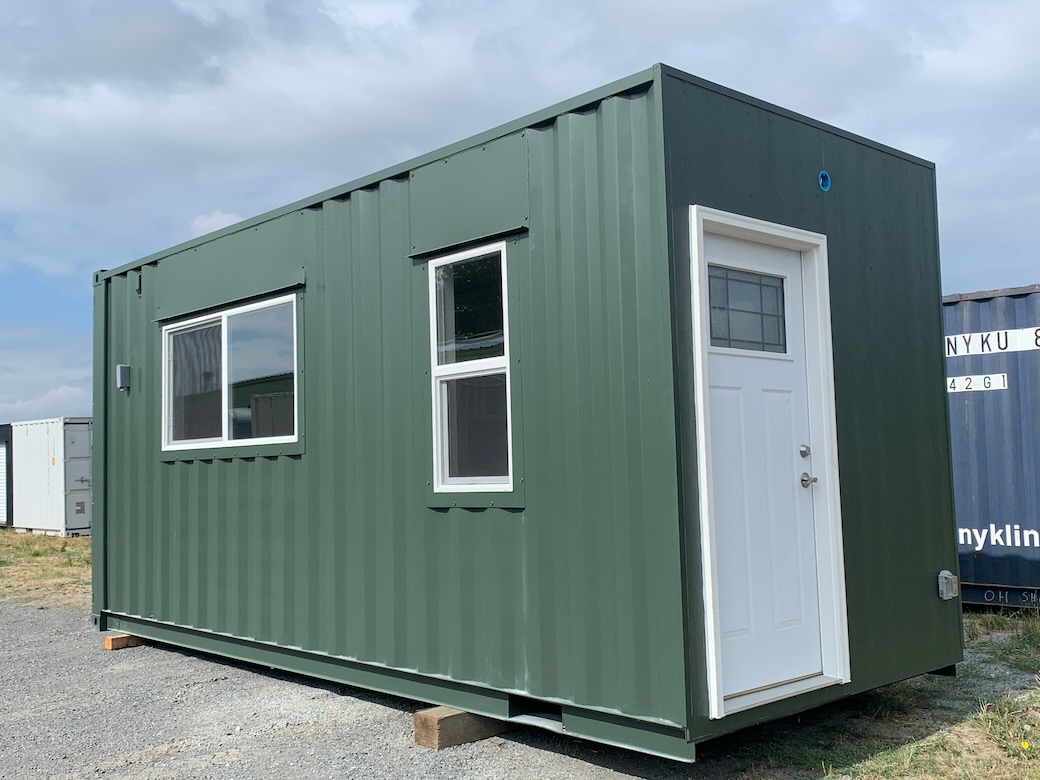green 20 foot shipping container with two types of windows and a pedestrian door
