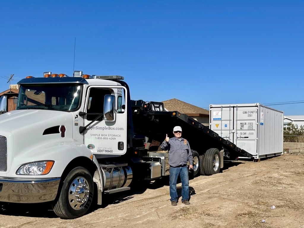 A friendly local Get Simple Box driver operating a specialized delivery truck to drop off a moving container rental exactly where the customer requested