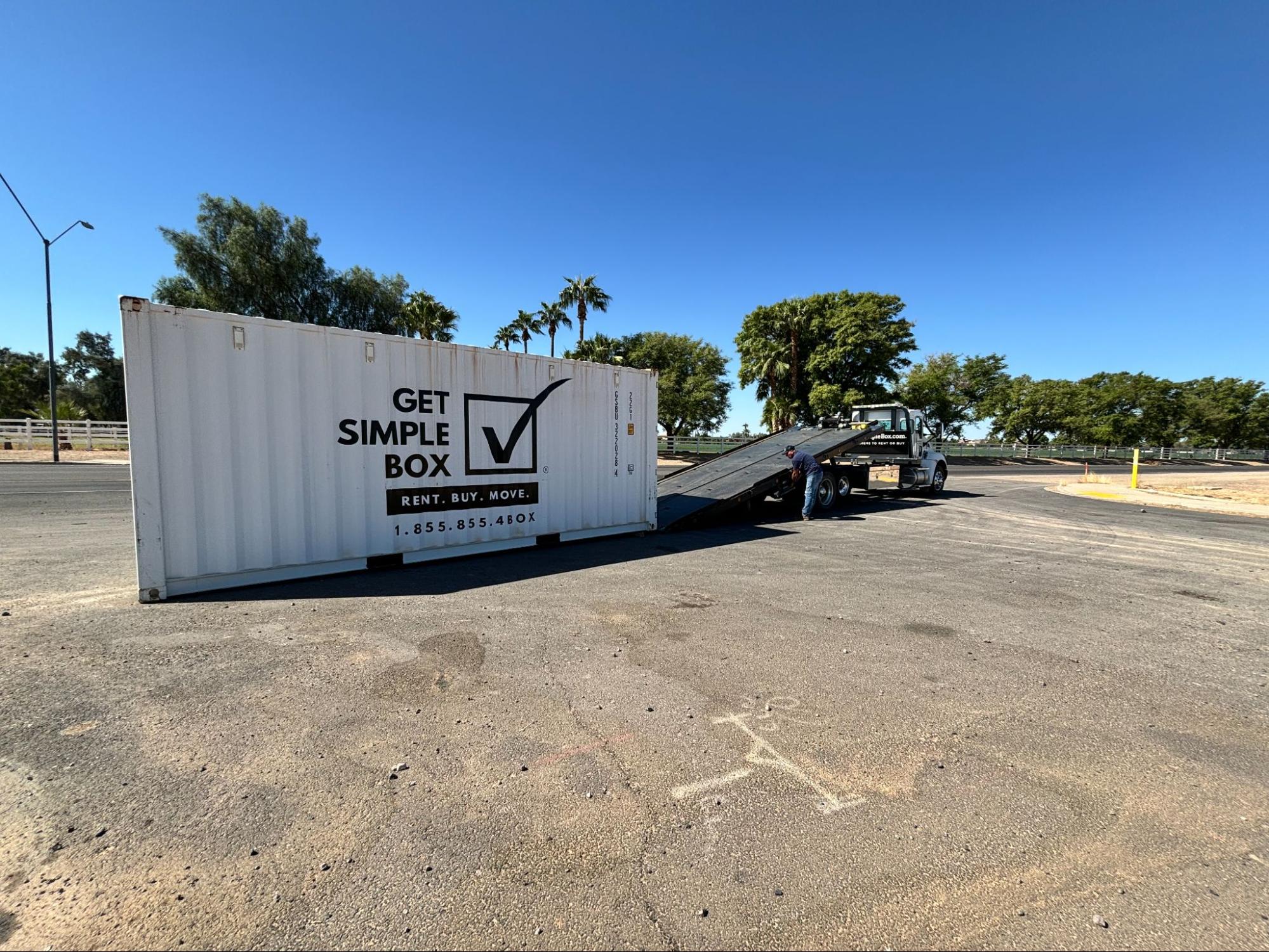 A professional Get Simple Box driver performing a precise storage container rental delivery using a specialized tilt-bed truck