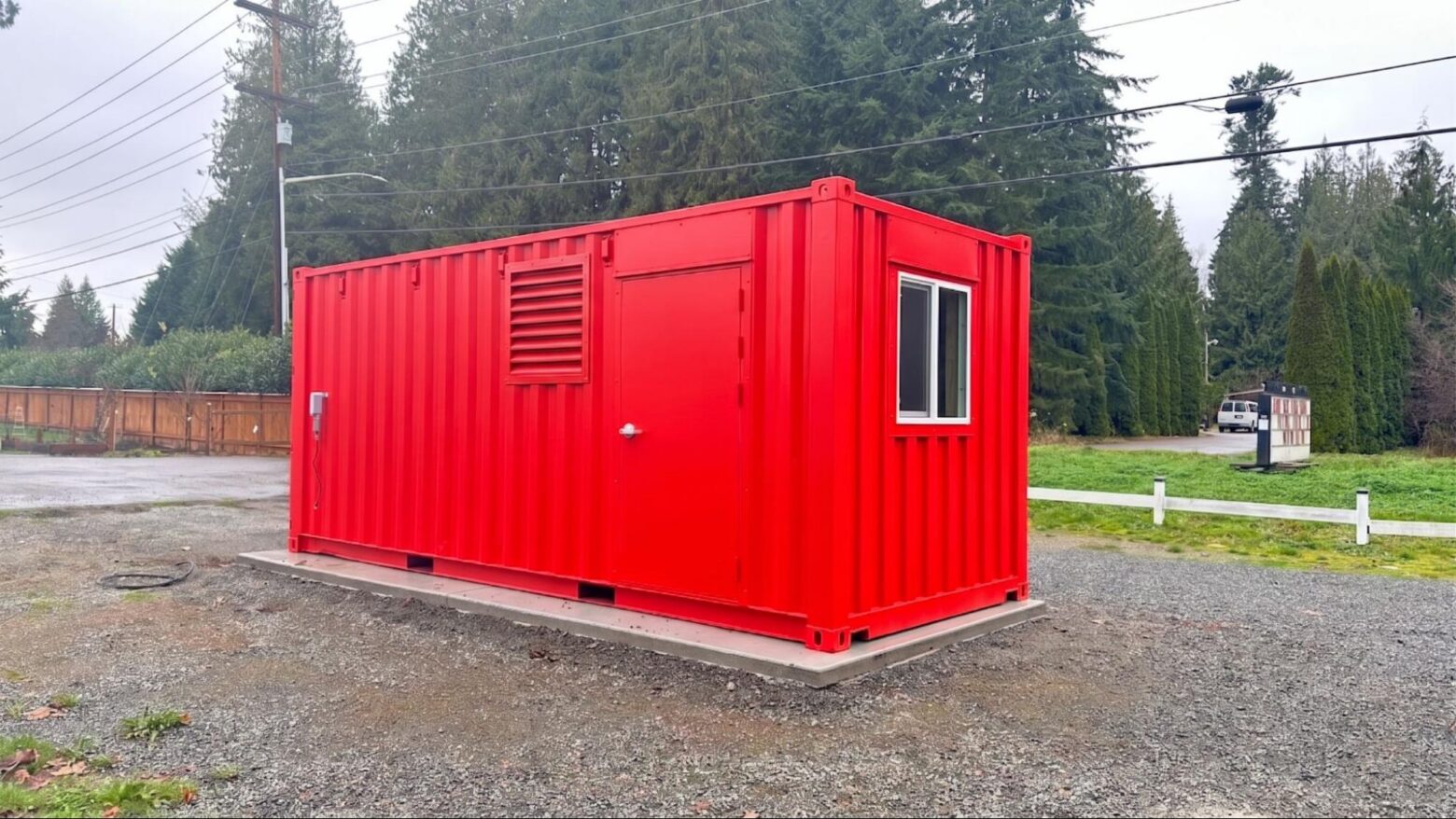 Red container with wall vents and a window on a gravel pad in Burlington, WA