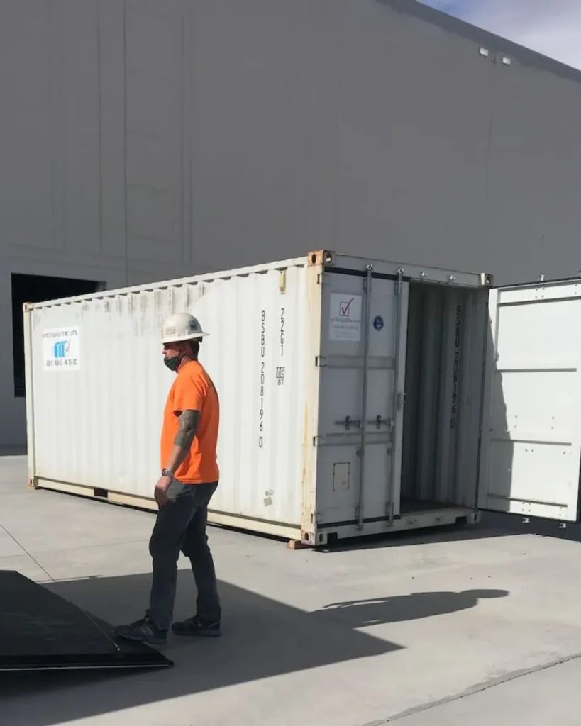 Worker standing beside an open white storage container