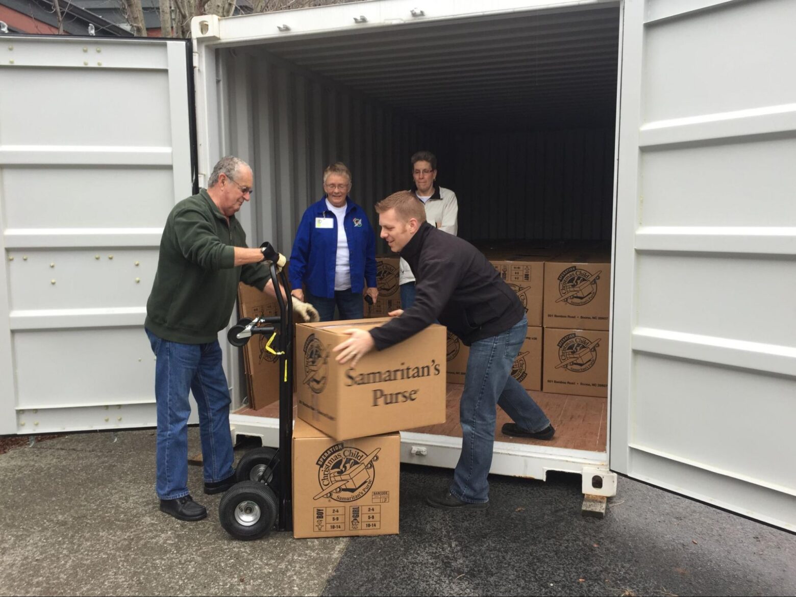 Volunteers loading boxes of donations into a 20-foot shipping container