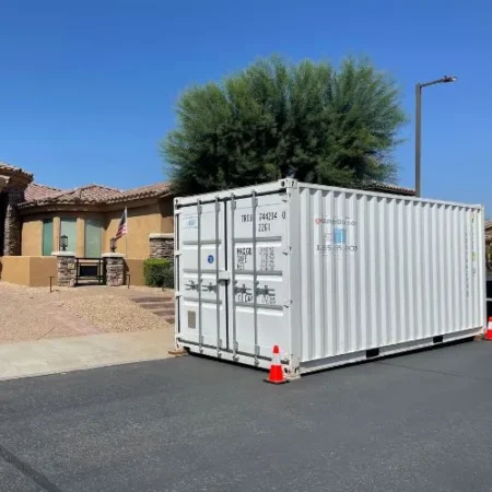 White shipping container placed on a residential street in front of a home