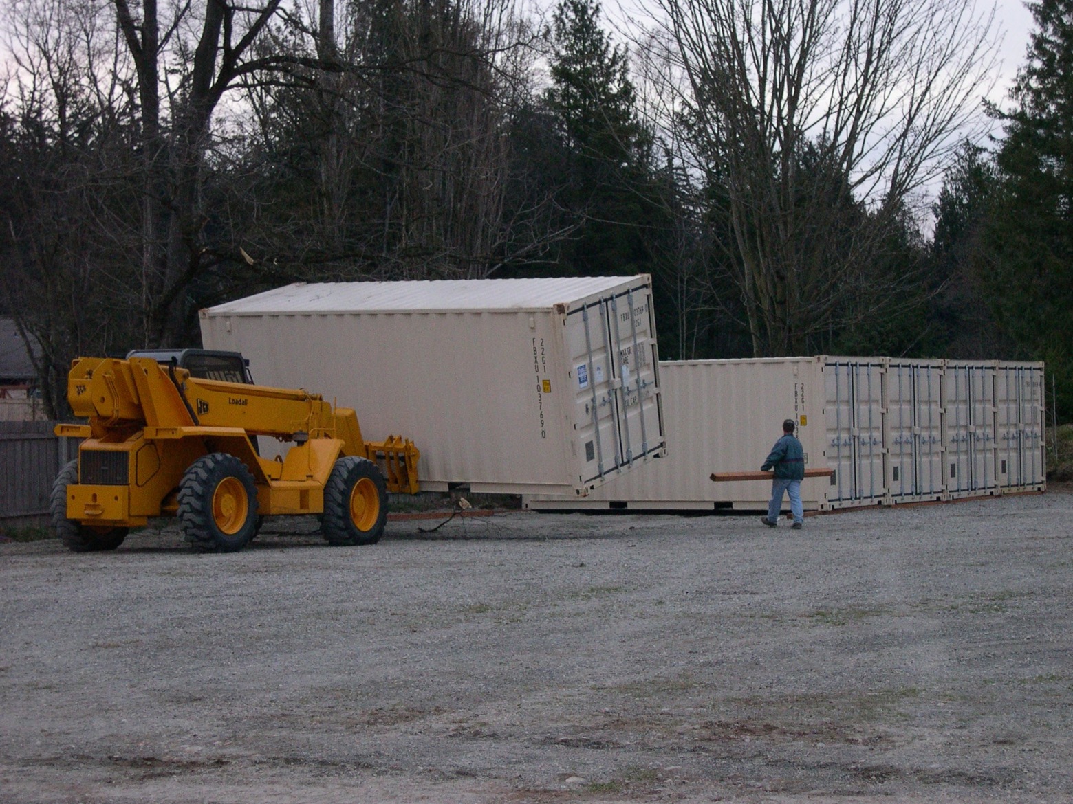 Loader moving shipping containers on an early storage lot surrounded by trees in Lynden, WA