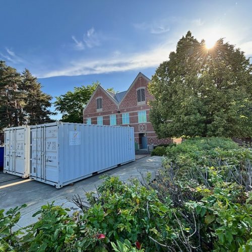 Two white storage containers outside a brick building
